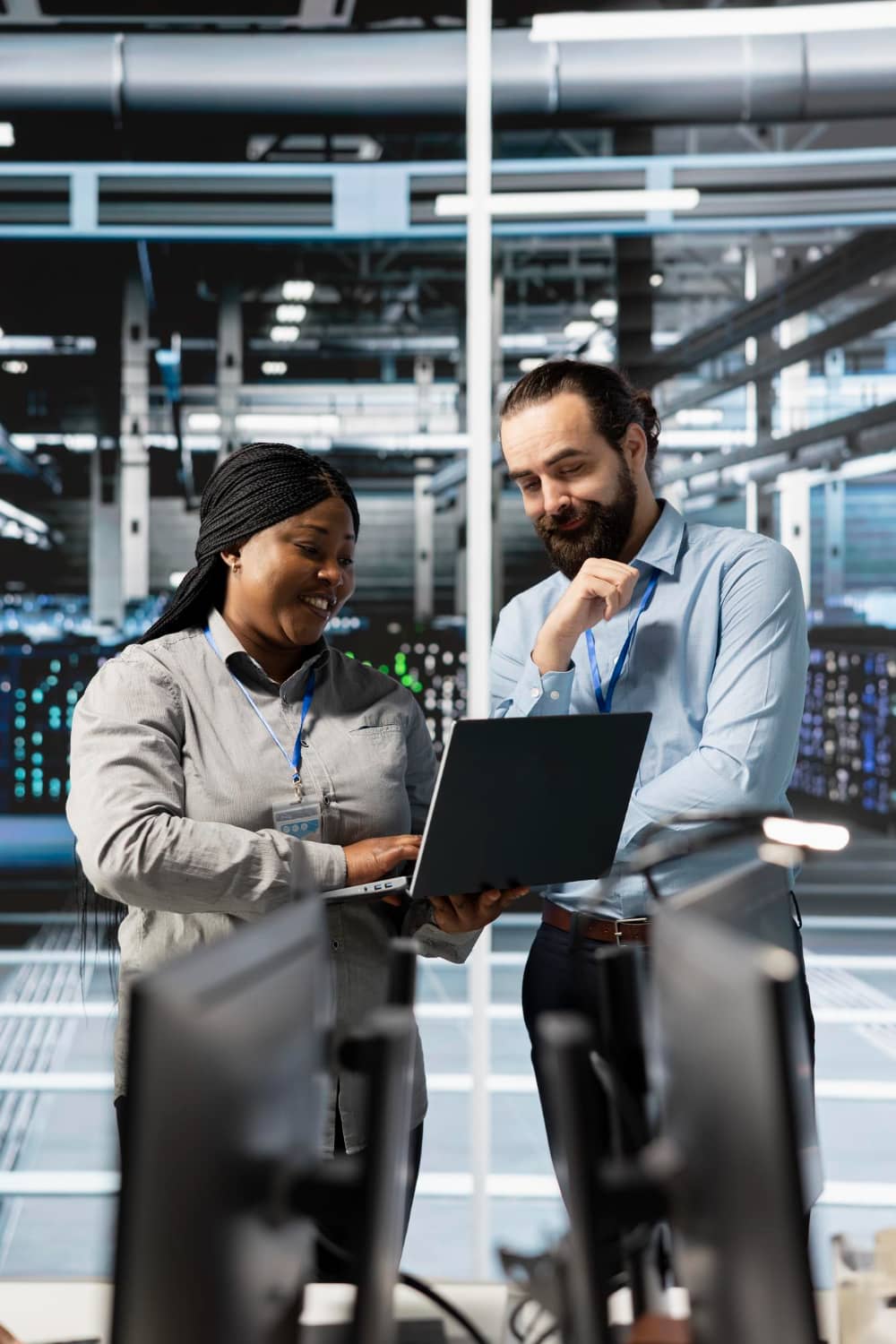 corporate img Two IT professionals collaborating while reviewing data on a laptop in a modern server room